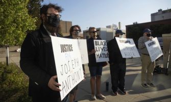 Protestors holding signs demanding justice for victims of gun violence, including Joseph Rosenbaum and Anthony Huber, at a demonstration related to the Rittenhouse case.