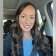 A woman smiling in a car, wearing a blue top and a black blazer. A woman smiling in a car, wearing a blue top and a black blazer.