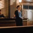 A lawyer giving a presentation in a courtroom, with a judge seated in the background. A lawyer giving a presentation in a courtroom, with a judge seated in the background.