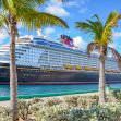 A Disney cruise ship docked near palm trees under a clear blue sky. A Disney cruise ship docked near palm trees under a clear blue sky.