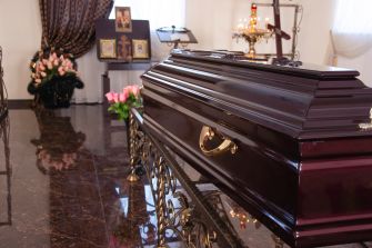 A closed casket in a funeral home setting, surrounded by flowers and memorial items.