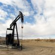 An oil drilling pumpjack standing in a barren landscape under a cloudy sky. An oil drilling pumpjack standing in a barren landscape under a cloudy sky.