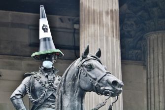 A statue wearing a traffic cone hat and a face mask, symbolizing protests against racial injustice.