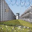 A view of the prison yard surrounded by fencing and barbed wire, highlighting the isolation of solitary confinement areas. A view of the prison yard surrounded by fencing and barbed wire, highlighting the isolation of solitary confinement areas.