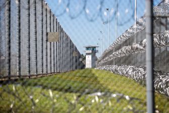 A view of the prison yard surrounded by fencing and barbed wire, highlighting the isolation of solitary confinement areas.