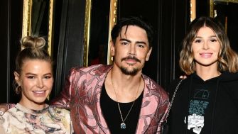 A group of three individuals posing together at an event, featuring a man in a patterned blazer and two women, one in a graphic sweatshirt and the other in a stylish top.