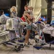 A family with children gathers at an airport terminal, surrounded by luggage on trolleys. A family with children gathers at an airport terminal, surrounded by luggage on trolleys.