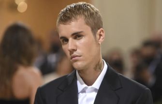 Justin Bieber at an event, looking serious in a formal outfit.
