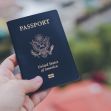 A person holding a U.S. passport against a blurred background. A person holding a U.S. passport against a blurred background.