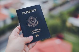 A person holding a U.S. passport against a blurred background.