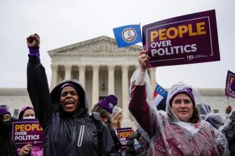 Demonstrators holding signs that say "People Over Politics" outside the U.S. Supreme Court building.