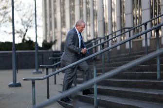 A man in a suit walking up the steps of a building, presumably related to a legal case.