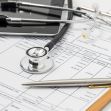 A stethoscope, pen, and medical forms on a clipboard, representing healthcare services and billing. A stethoscope, pen, and medical forms on a clipboard, representing healthcare services and billing.