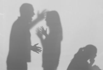 Silhouettes of a couple arguing, representing domestic conflict, with a third figure sitting apart, suggesting emotional distress.