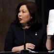 A woman holds a document while speaking at a Senate hearing. A woman holds a document while speaking at a Senate hearing.