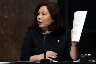 A woman holds a document while speaking at a Senate hearing.