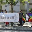 A group of protesters holding a banner reading "TRANS KIDS ARE LOVED" alongside flags supporting LGBTQ+ rights. A group of protesters holding a banner reading "TRANS KIDS ARE LOVED" alongside flags supporting LGBTQ+ rights.