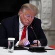 Donald Trump sitting at a table, looking down at his phone with a serious expression. Donald Trump sitting at a table, looking down at his phone with a serious expression.