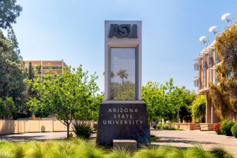 Sign for Arizona State University on campus, surrounded by greenery.