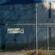 A view of the exterior of Alameda County Jail, featuring a "No Trespassing" sign and barbed wire fencing. A view of the exterior of Alameda County Jail, featuring a "No Trespassing" sign and barbed wire fencing.
