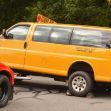 Image of a yellow school van on a tow truck, with police presence at the scene. Image of a yellow school van on a tow truck, with police presence at the scene.