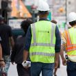 Construction workers in safety vests and hard hats walking on a busy New York City street. Construction workers in safety vests and hard hats walking on a busy New York City street.