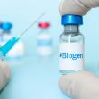 A hand holding a vial labeled with the Biogen logo, with a syringe positioned nearby, against a light blue background. A hand holding a vial labeled with the Biogen logo, with a syringe positioned nearby, against a light blue background.