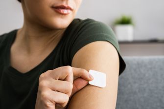 A woman applying a transdermal birth control patch on her arm.