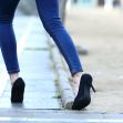A woman in high heels walking along a sidewalk, highlighting potential tripping hazards. A woman in high heels walking along a sidewalk, highlighting potential tripping hazards.