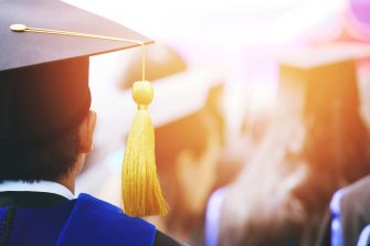 A graduate wearing a cap and gown at a graduation ceremony, with a focus on the cap's tassel.