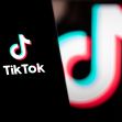 Close-up of a smartphone displaying the TikTok logo and a background image of the TikTok emblem illuminated in neon colors. Close-up of a smartphone displaying the TikTok logo and a background image of the TikTok emblem illuminated in neon colors.
