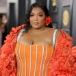 Lizzo posing on the red carpet at an event, wearing a vibrant orange outfit with floral accents. Lizzo posing on the red carpet at an event, wearing a vibrant orange outfit with floral accents.