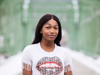 Portrait of a transgender woman standing on a bridge, celebrating policy changes for transgender rights.