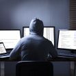 A person in a hoodie working on multiple computers, seemingly engaged in hacking activities. A person in a hoodie working on multiple computers, seemingly engaged in hacking activities.