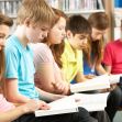 A group of children sitting in a row, focused on reading books in a library setting. A group of children sitting in a row, focused on reading books in a library setting.