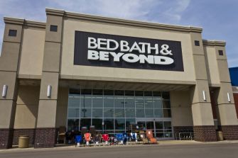 Exterior of a Bed Bath & Beyond store with chairs set up in front.