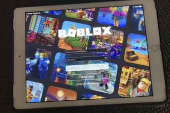 Screenshot of the Roblox login screen displayed on a tablet, featuring various game images in the background.