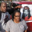 A man and woman stand in front of a vehicle displaying a poster of Kendrick Johnson, expressing their grief and determination to seek answers about his death. A man and woman stand in front of a vehicle displaying a poster of Kendrick Johnson, expressing their grief and determination to seek answers about his death.