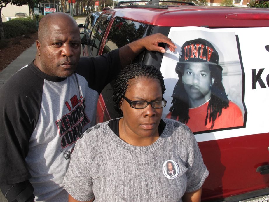 Kenneth and Jacquelyn Johnson stand next to a banner on their SUV showing their late son Kendrick, in Valdosta, Ga., in December 2013.