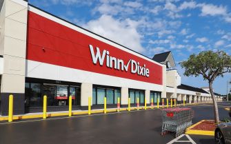 Exterior view of a Winn-Dixie supermarket building with shopping carts outside.