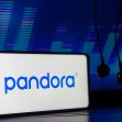 A smartphone displaying the Pandora logo with headphones in the foreground, set against a colorful digital backdrop. A smartphone displaying the Pandora logo with headphones in the foreground, set against a colorful digital backdrop.