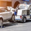 A towing vehicle lifting a silver car, illustrating the towing process involved in vehicle repossession. A towing vehicle lifting a silver car, illustrating the towing process involved in vehicle repossession.