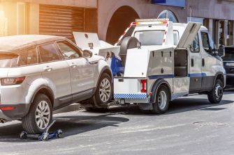 A towing vehicle lifting a silver car, illustrating the towing process involved in vehicle repossession.
