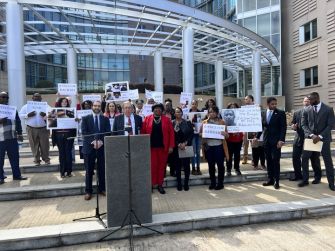 A group of supporters and advocates holding signs at a press conference addressing the lawsuit filed by former inmate Susie Balfour against the Mississippi Department of Corrections for delayed cancer diagnosis and inadequate medical care.