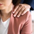 A close-up of a woman's shoulder with a man's hand placed on it, symbolizing inappropriate physical contact in a workplace setting. A close-up of a woman's shoulder with a man's hand placed on it, symbolizing inappropriate physical contact in a workplace setting.