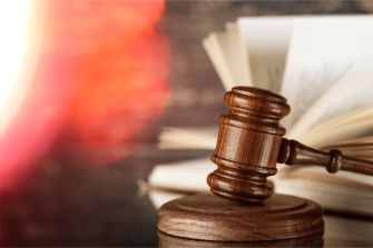A wooden gavel on a sound block with open books in the background, symbolizing a legal decision or court ruling.