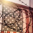 An American flag partially obscured by barbed wire, symbolizing border security and immigration issues. An American flag partially obscured by barbed wire, symbolizing border security and immigration issues.