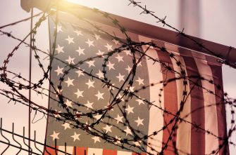 An American flag partially obscured by barbed wire, symbolizing border security and immigration issues.