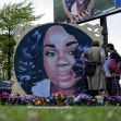 Memorial mural of Breonna Taylor with visitors paying their respects, surrounded by flowers. Memorial mural of Breonna Taylor with visitors paying their respects, surrounded by flowers.