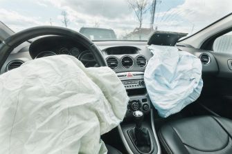 Interior view of a car with deployed airbags on the driver's side and passenger's side.